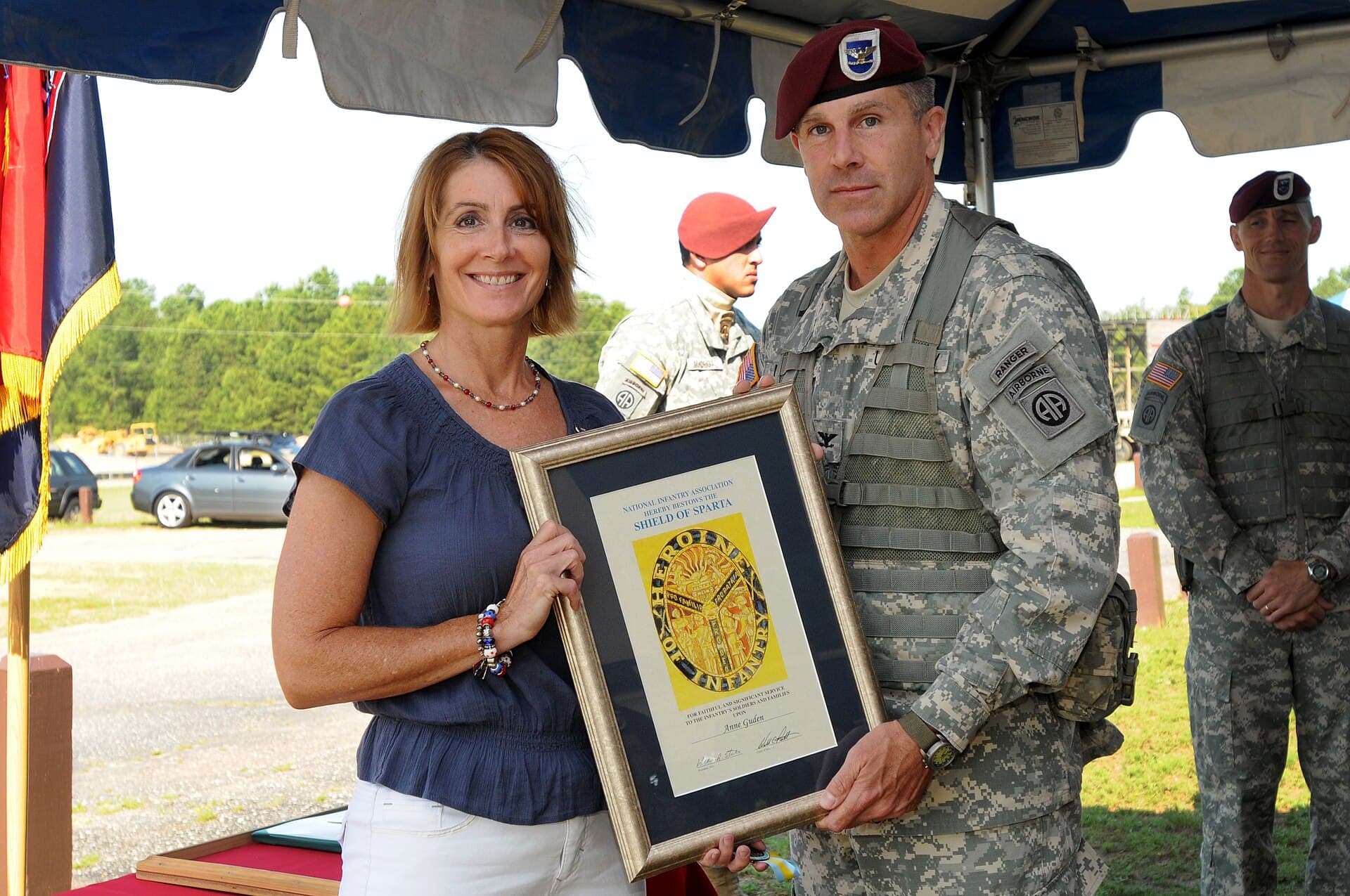 Sparta — U.S. Army Col. Timothy McAteer, foreground right, commander of the 2nd Brigade Combat Team (BCT), 82nd Airborne Division, presents the Shield of Sparta award to Anne Guden during her husband Command Sgt. Maj 120628-A-FO214-793
